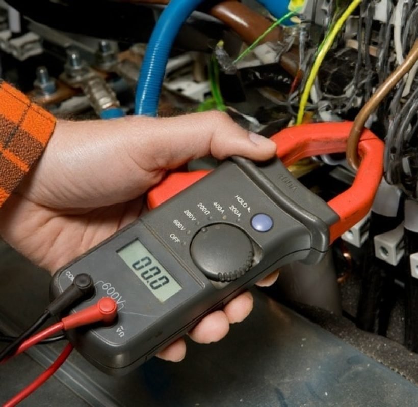 Pruebas de aislamiento y control de carga de líneas: técnico utilizando multímetro de pinza para detección de sobrecalentamiento e intervención rápida ante disparos continuos en sistemas eléctricos industriales.